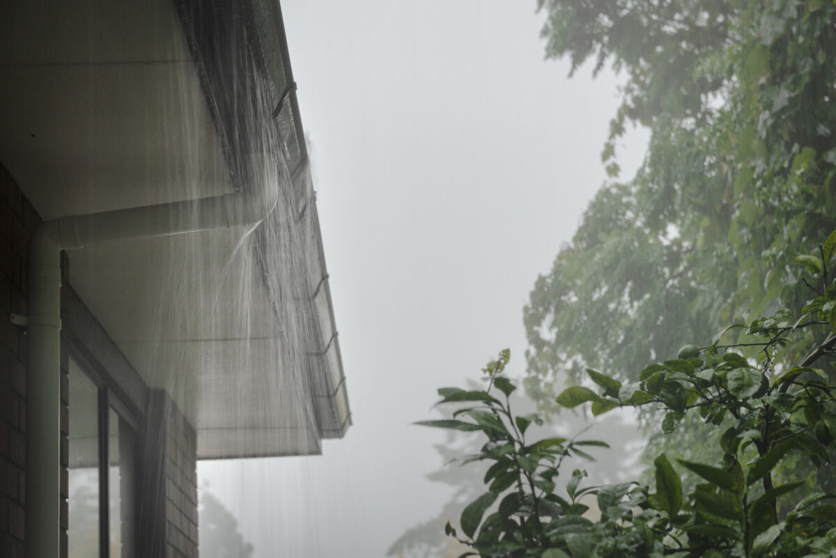 Roof gutter overflow in the heavy rain. Rain water cascading over the gutter.